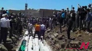 People gather at a mass burial for the victims of an artillery barrage from Syrian forces, in Houla